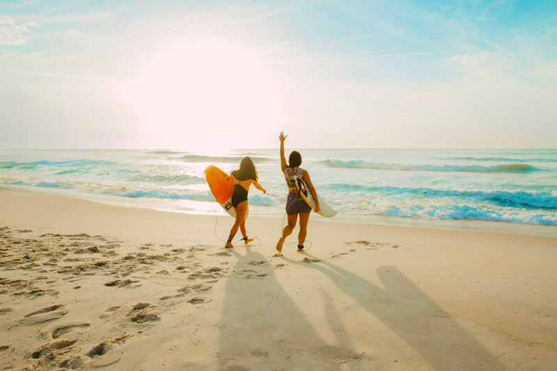 long islanders walking to the water with their surfboards